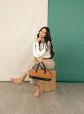 Model sitting with Qu!rk Boutique tan and black satchel bowler bag, spring collection