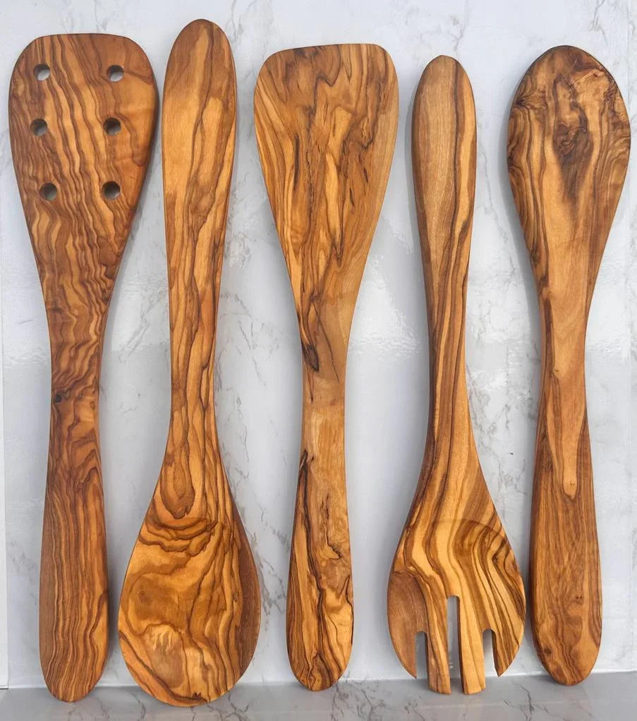 Set of five handcrafted olive wood kitchen utensils on white marble background