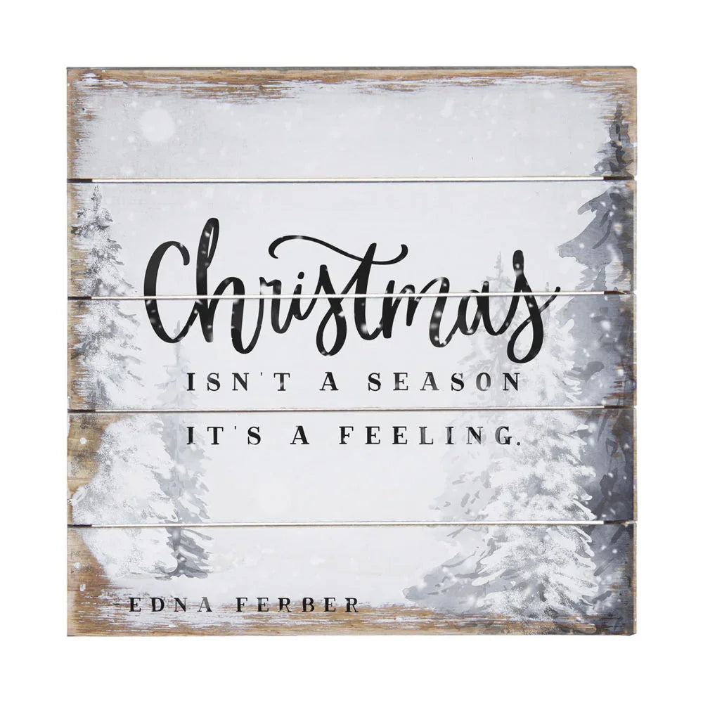 Rustic wooden sign with snowy pine trees and quote: Christmas isn't a season, it's a feeling