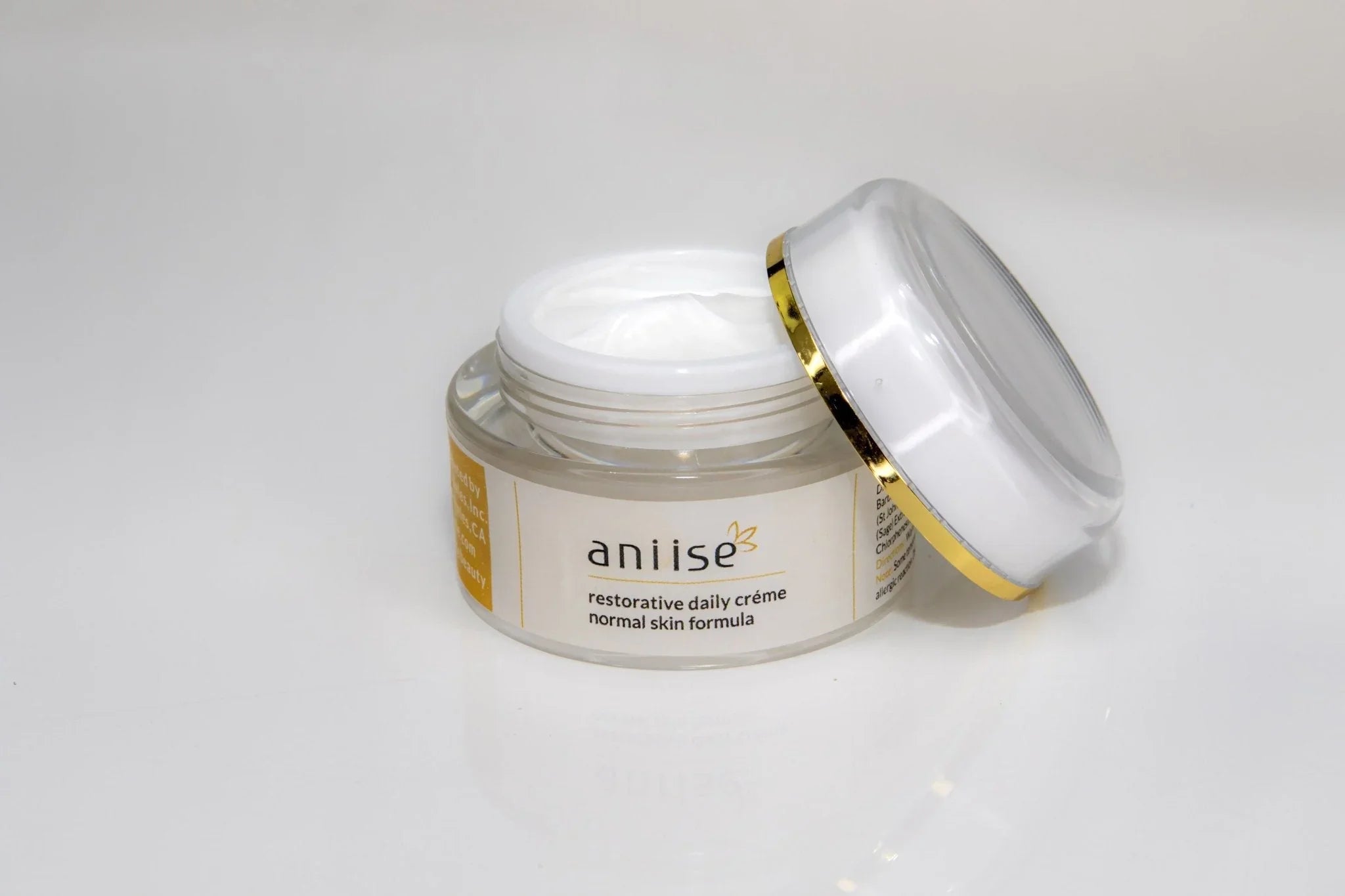 Aniise restorative daily crème for normal skin in a clear jar with white and gold lid on white background