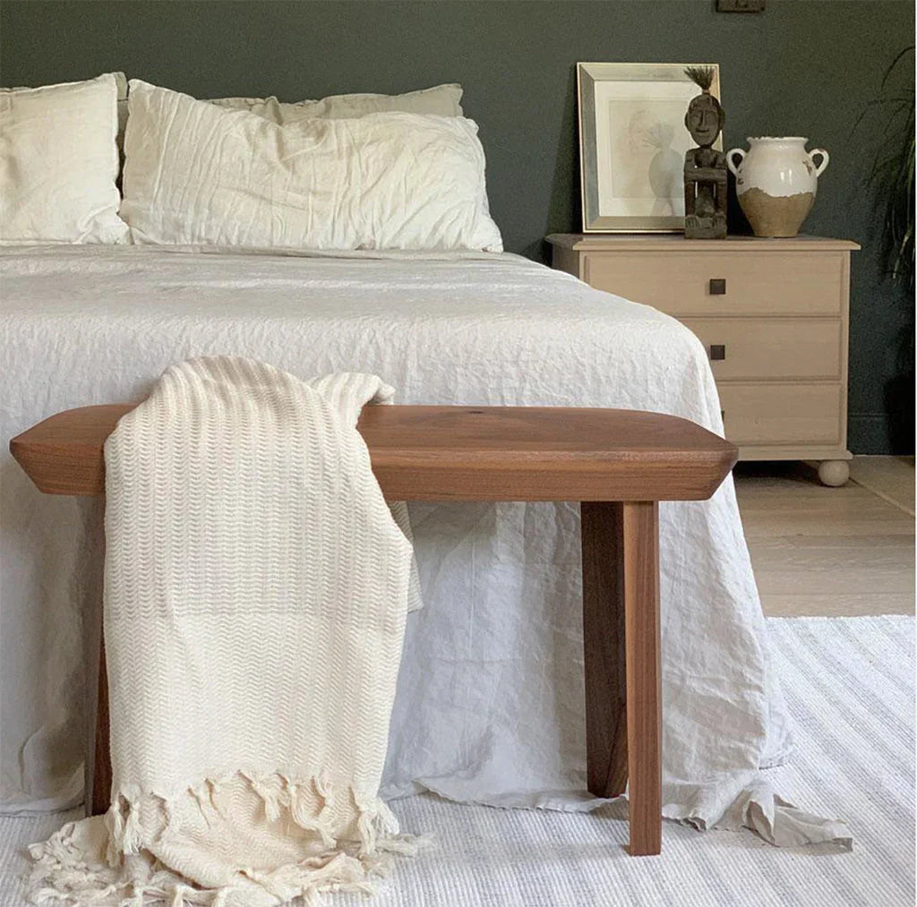Ivory throw blanket draped on wooden bench in cozy, modern bedroom at Qu!rk Boutique