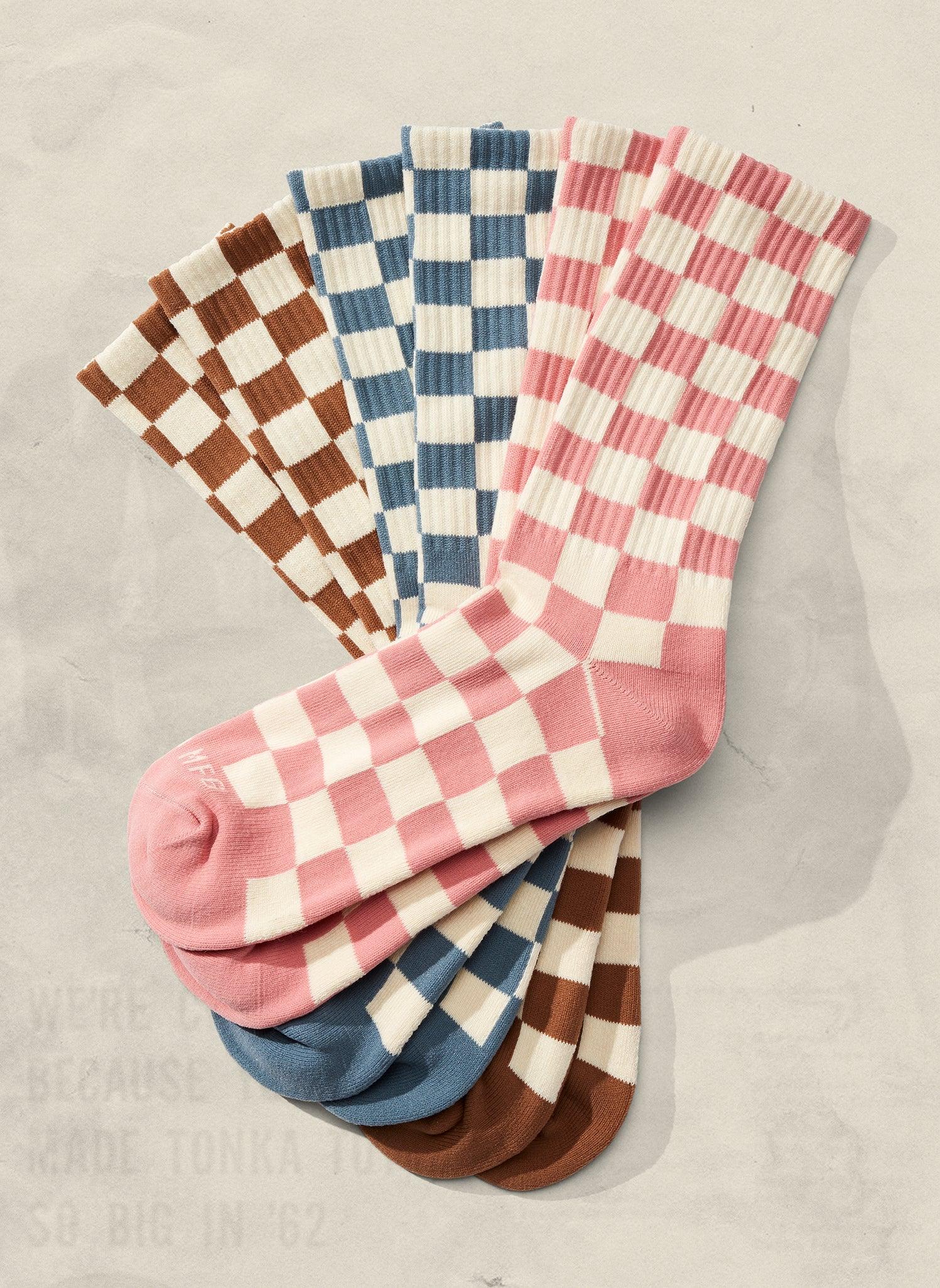 Stack of artist-designed checkered socks in brown, blue, and pink at Qu!rk Boutique