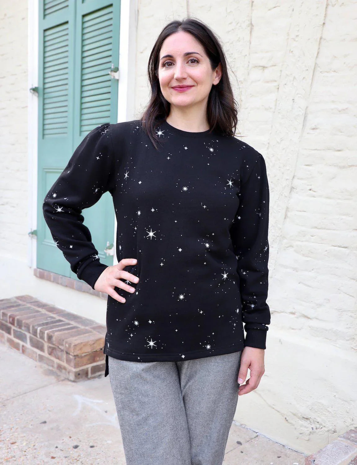Woman models black organic fleece sweater with white star print, outside Qu!rk Boutique