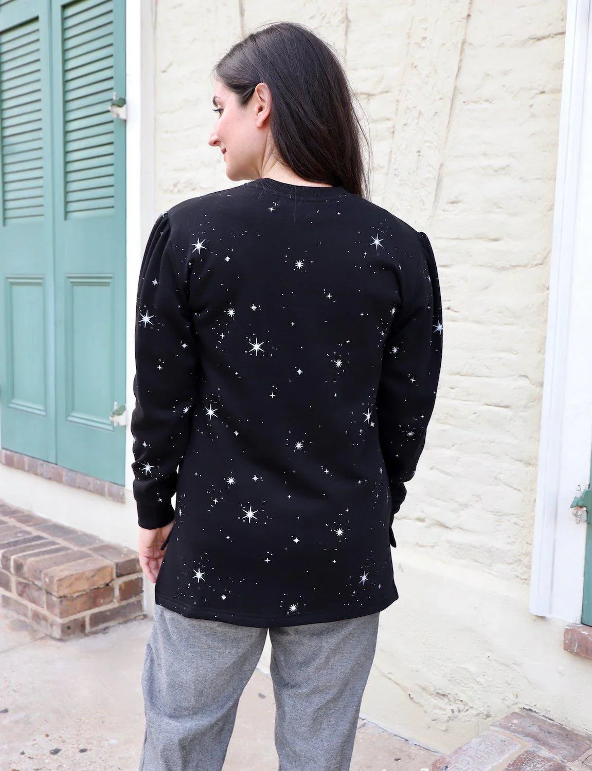 Woman wearing black star-print organic fleece sweater from Qu!rk Boutique, outdoor scene