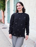 Woman wearing a black star-print organic fleece sweater from Qu!rk Boutique outdoors