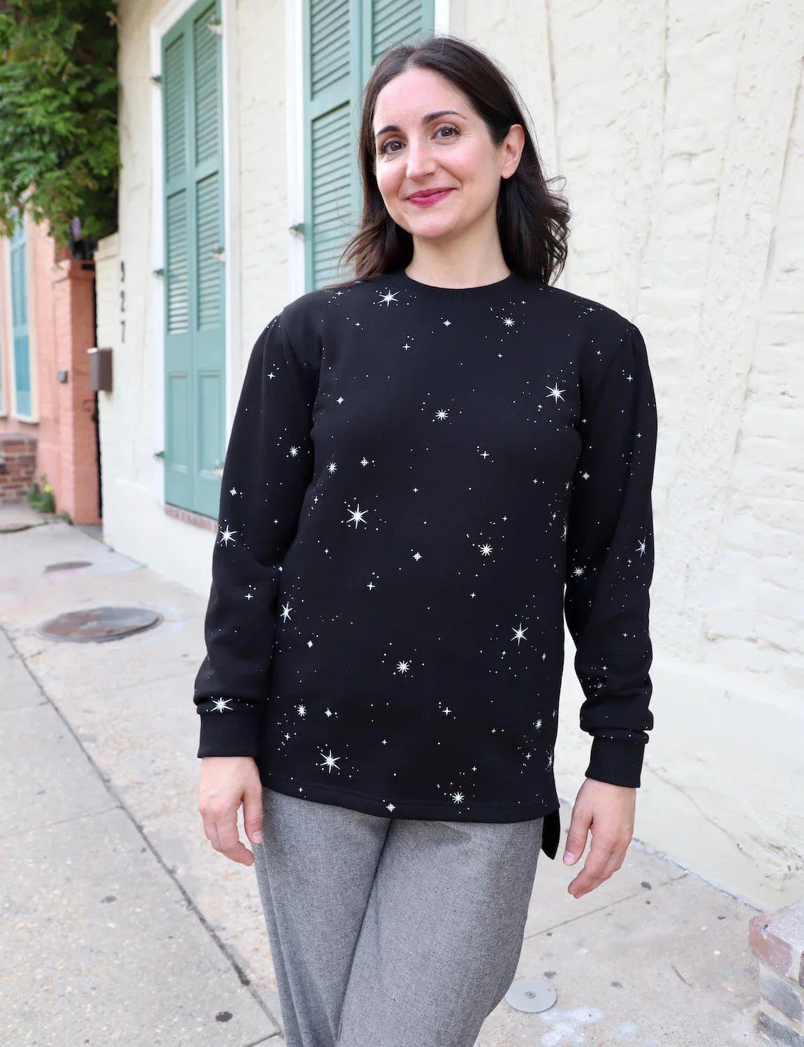Woman wearing a black star-print organic fleece sweater from Qu!rk Boutique outdoors