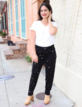 Woman wearing black star-patterned organic pants and white top outside boutique
