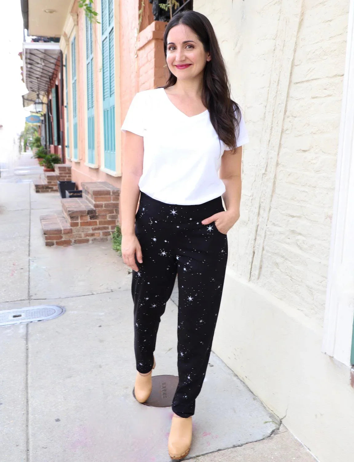 Woman in a white tee and star-print organic pants walks outside Qu!rk Boutique