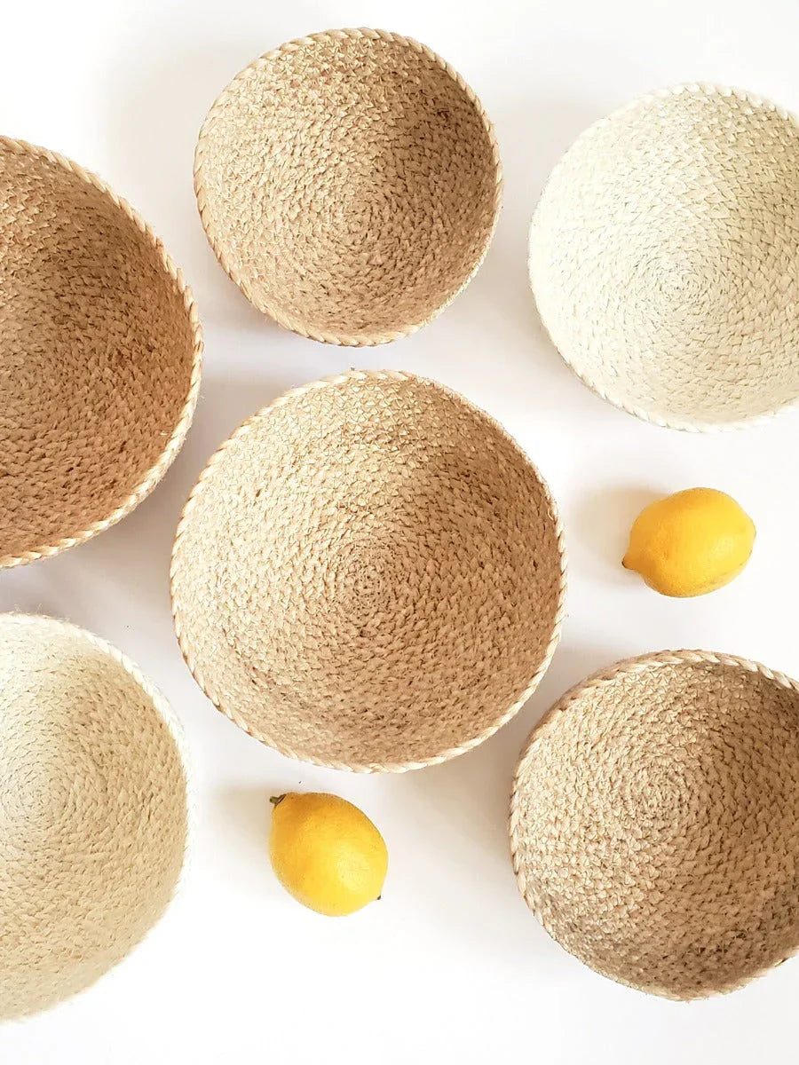 Set of six woven straw bowls in natural beige shades with two yellow lemons on white background