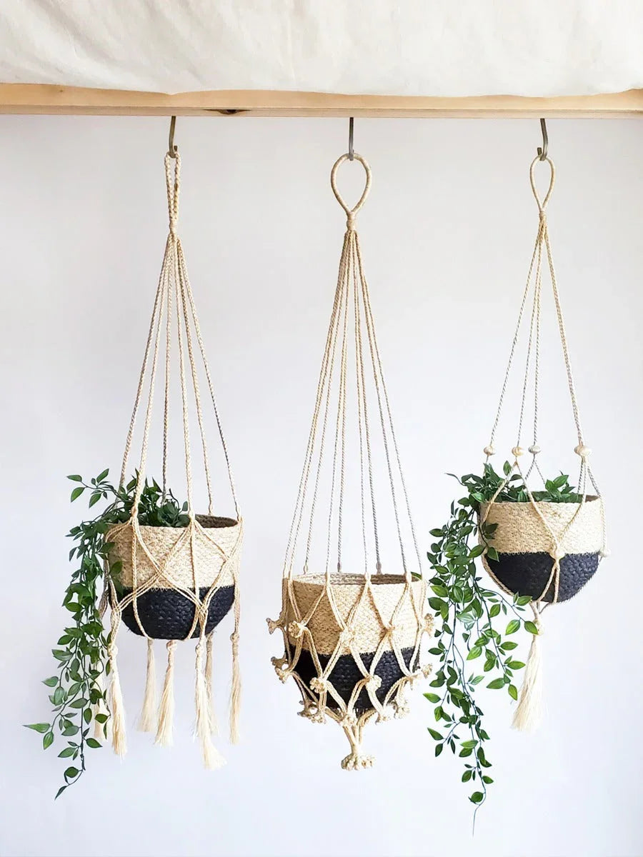Three black and natural woven hanging planters with green vines, displayed on a wooden rod at Qu!rk Boutique.
