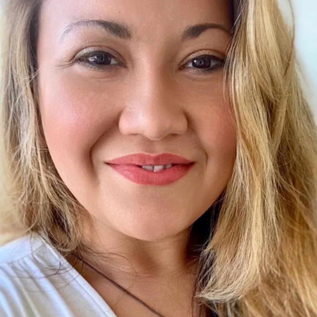 Smiling woman with long blonde hair, wearing natural makeup and a white top, close-up portrait