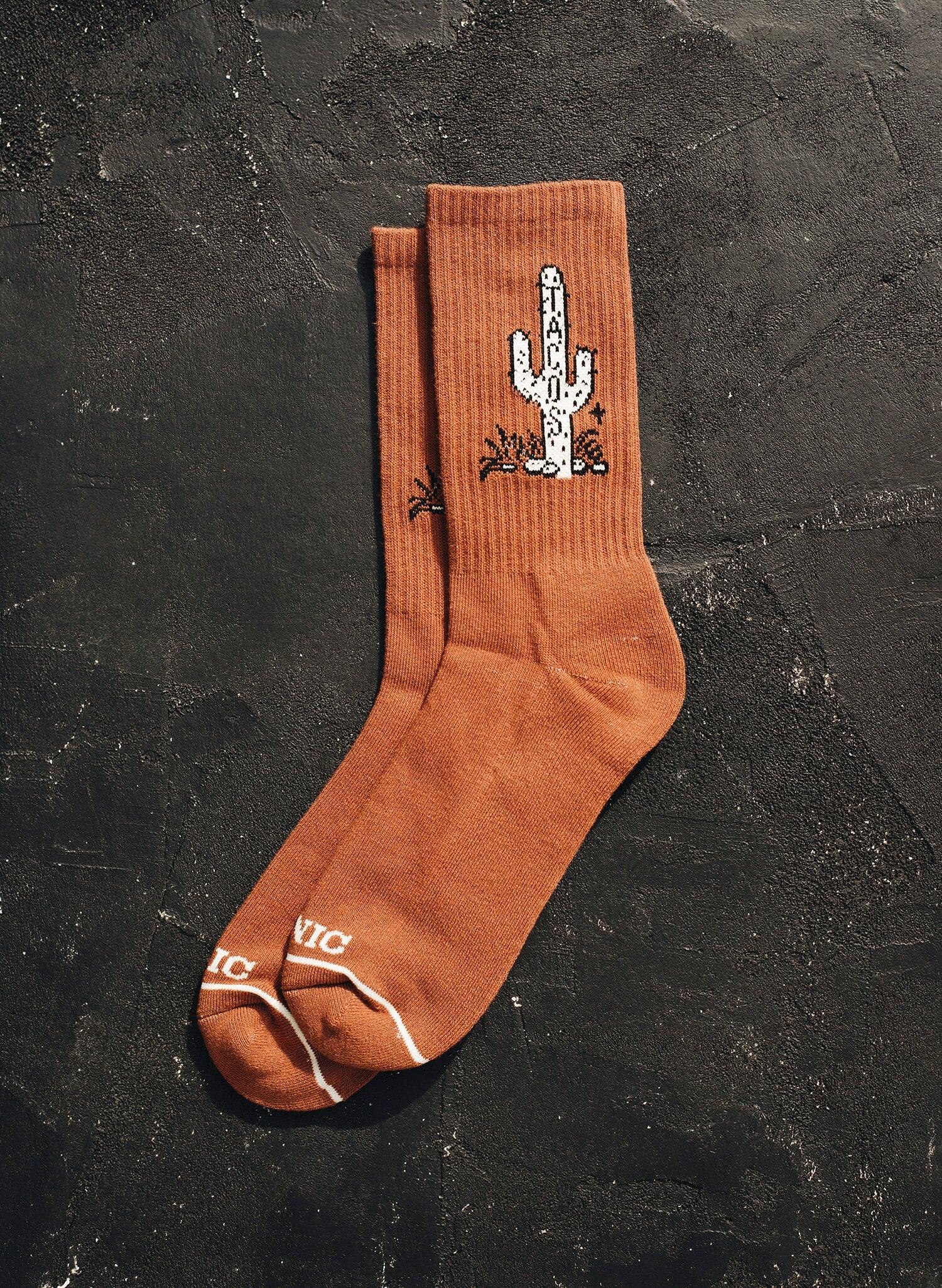 Rust orange socks with white cactus and Tacos text design on black textured background