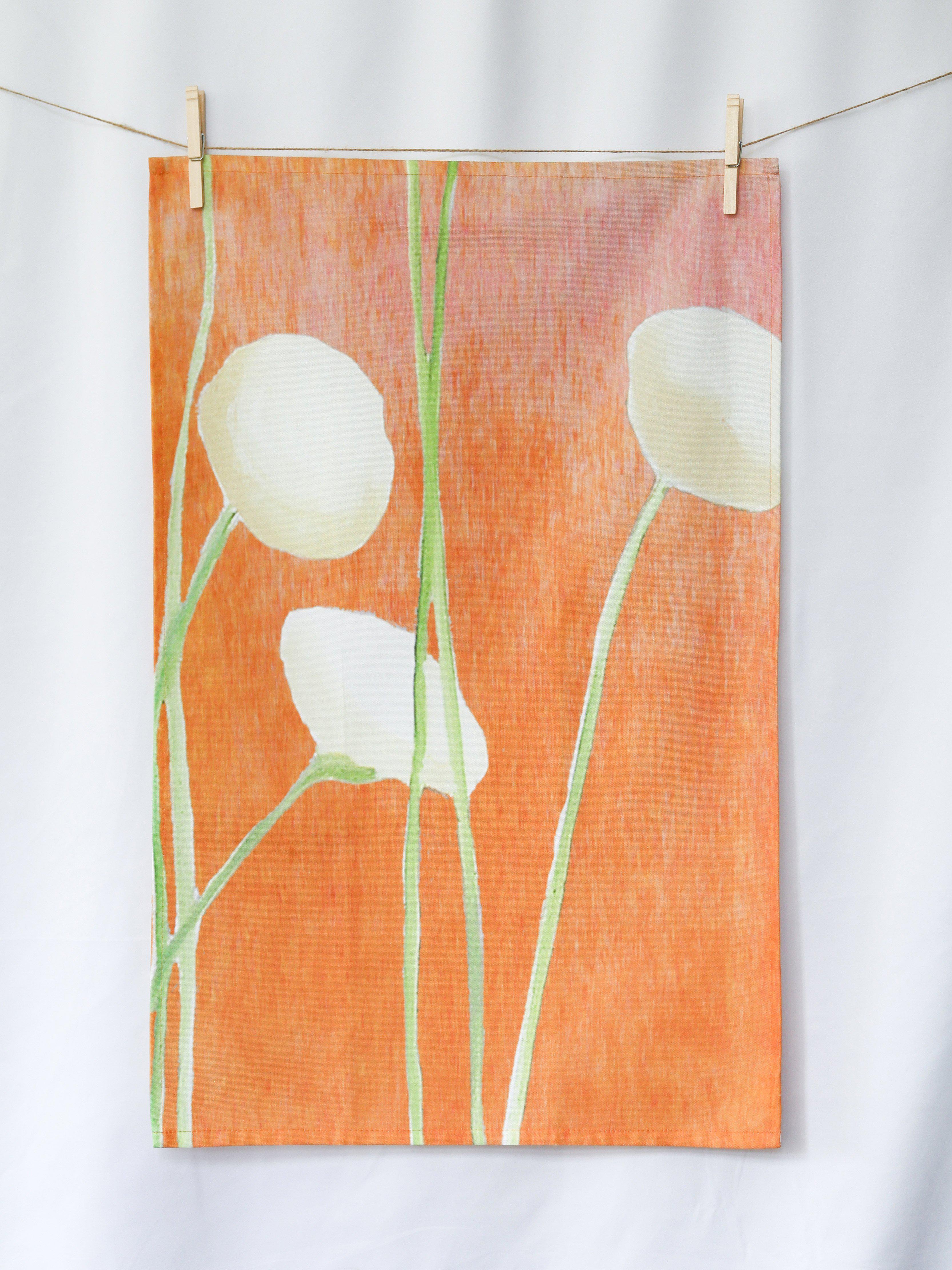 Cream flower design tea towel hanging on a line with wooden clothespins against white background