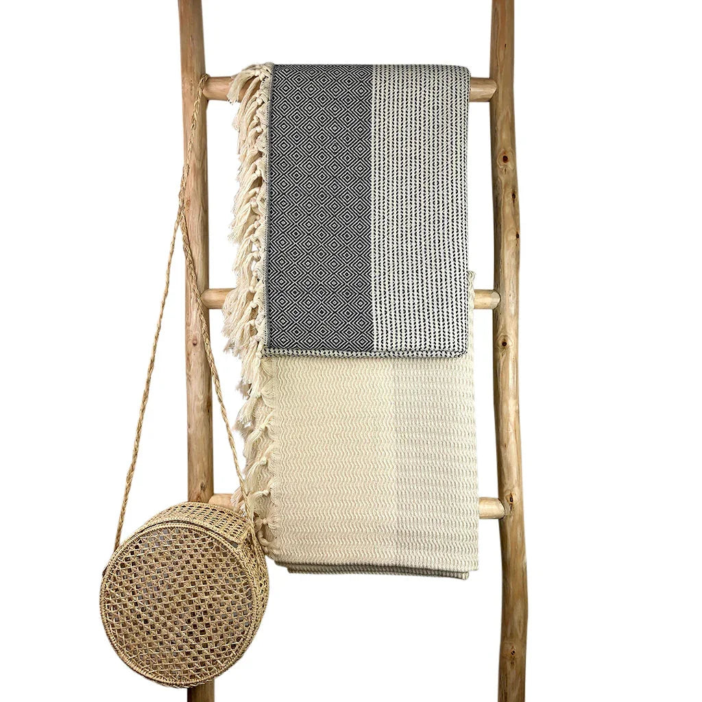 Turkish cotton throw blankets with fringe and woven straw bag on wooden ladder, boutique style