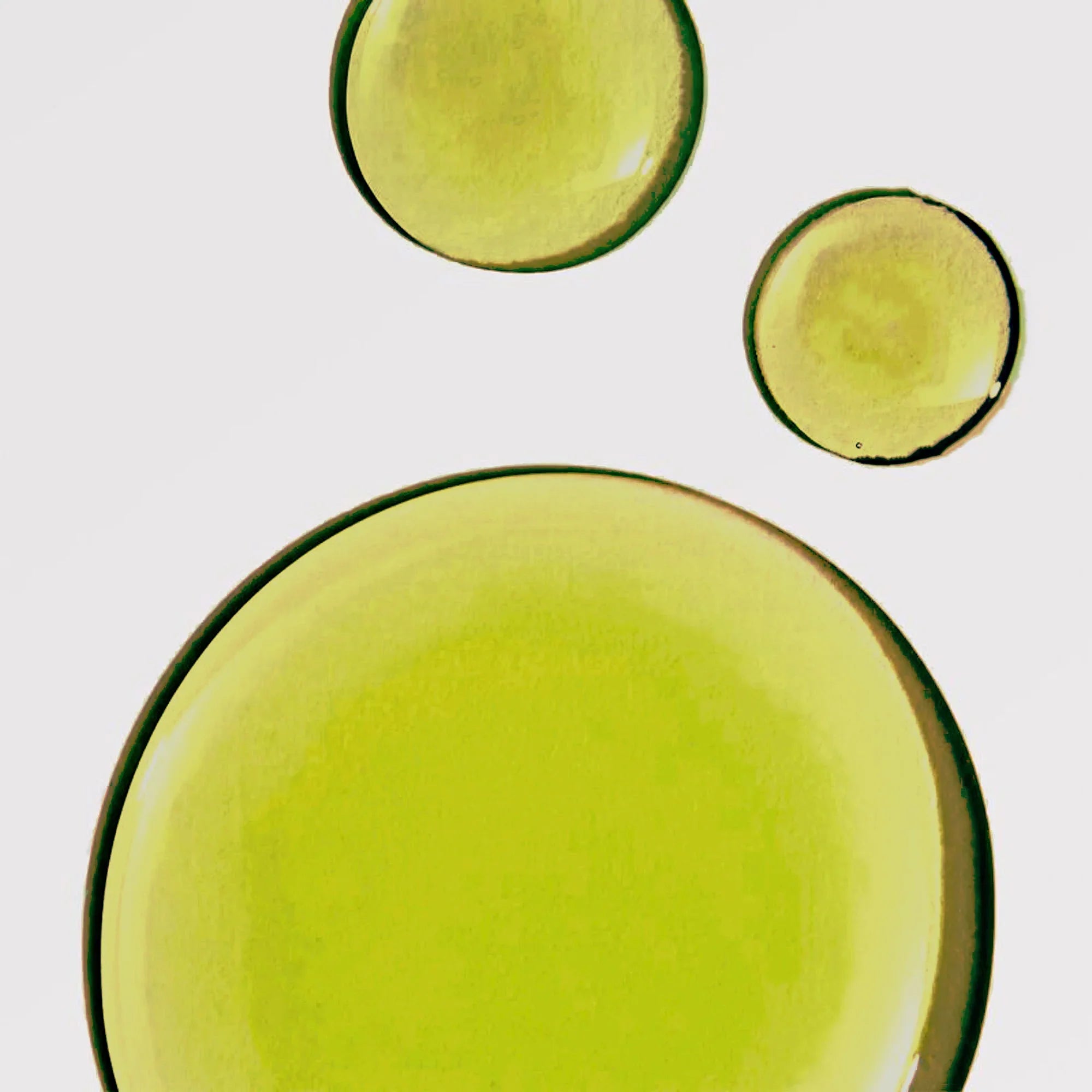 Close-up of three yellow-green oil drops on white, showcasing eco-friendly boutique skincare.