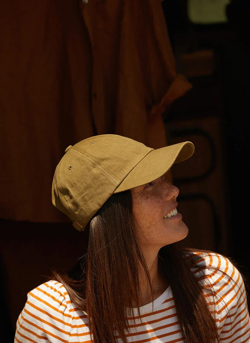 Woman wearing vintage washed khaki scout dad hat and striped shirt at Qu!rk Boutique