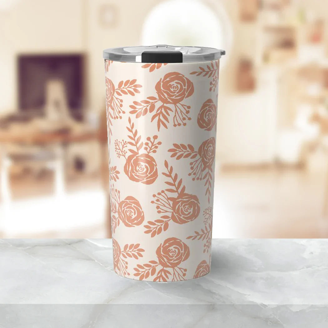 Tall stainless steel tumbler with light pink floral pattern and gray lid on marble countertop
