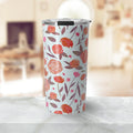 White travel tumbler with orange and pink floral pattern on marble table in blurred cozy room