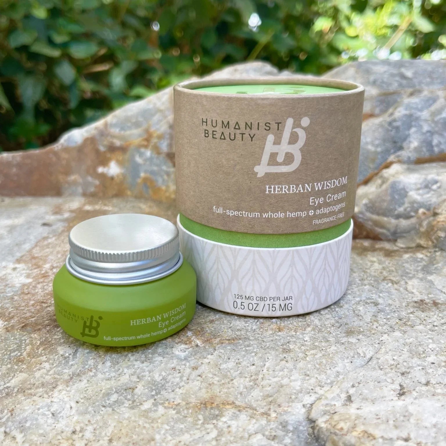 Herban Wisdom eye cream by Humanist Beauty, green jar and box on natural stone, eco-friendly skincare