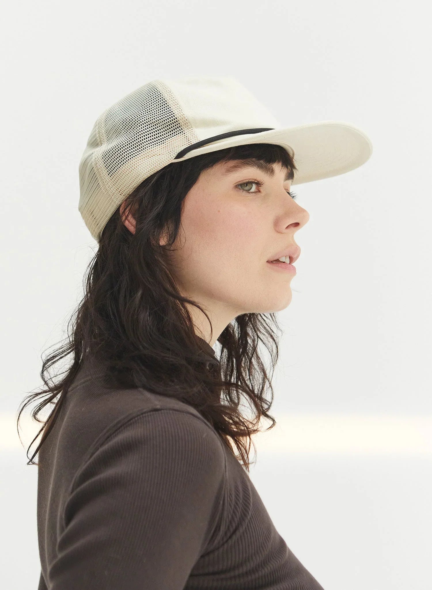 Woman wearing an eggshell cotton rope trucker hat from Qu!rk Boutique, side profile.