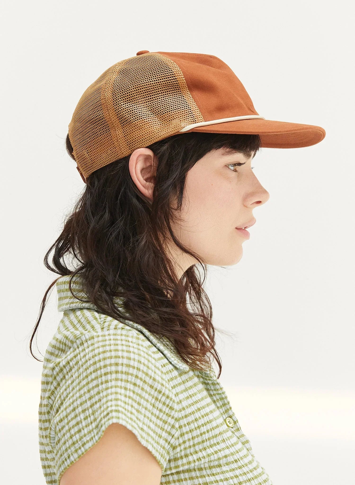 Woman wearing rust cotton mesh trucker hat, side profile, Qu!rk Boutique eco-friendly style