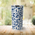 White travel tumbler with blue floral pattern and silver lid on wooden table