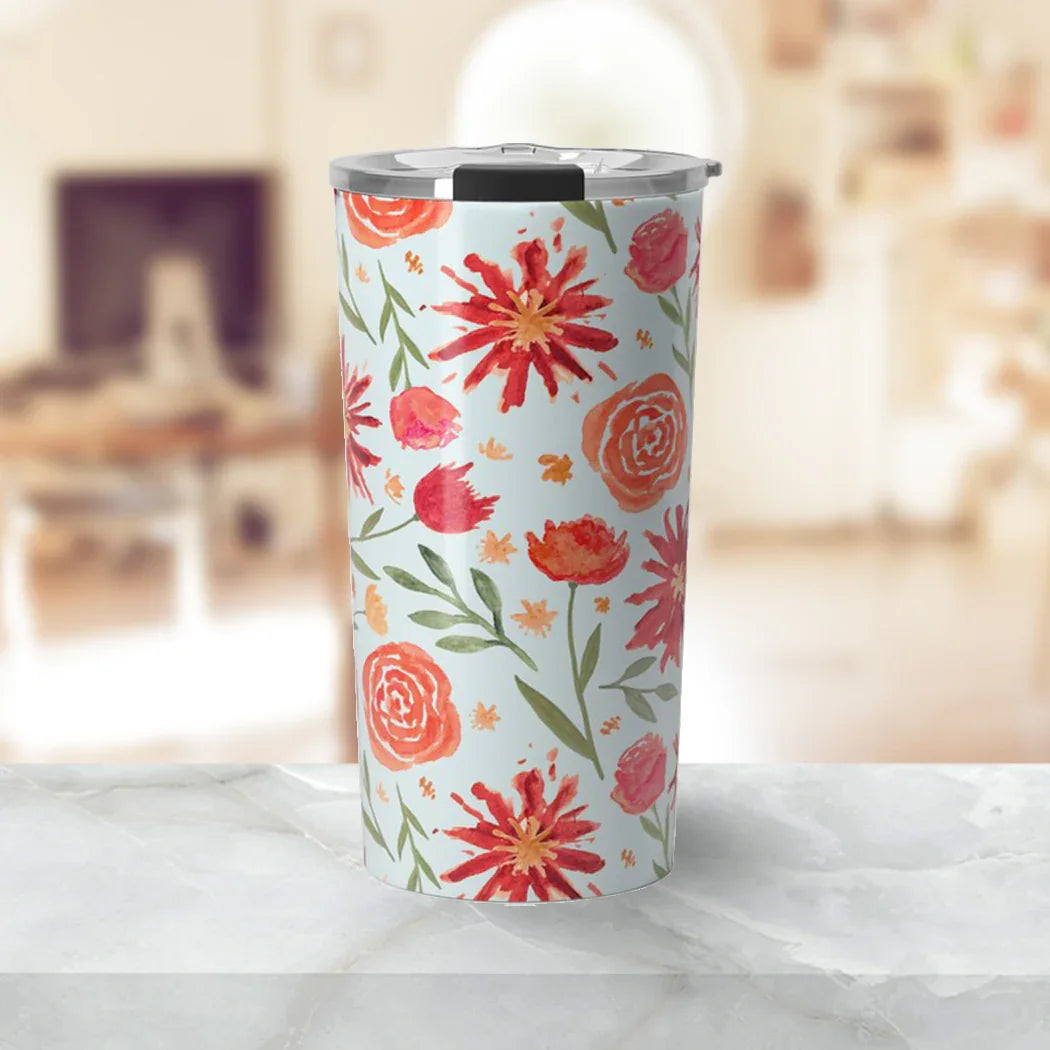 Insulated travel tumbler with red and orange floral pattern on light blue background on marble surface