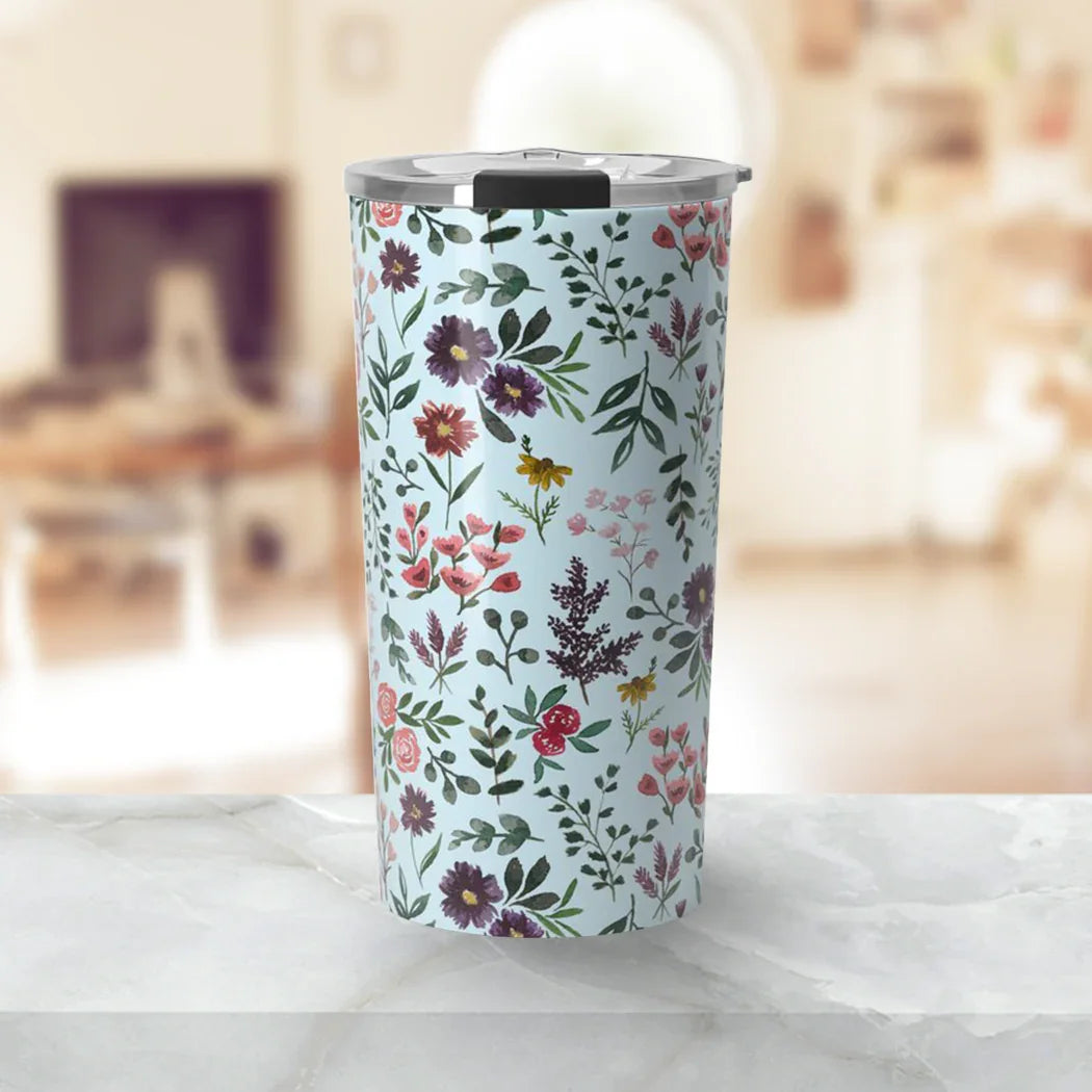 Floral patterned travel tumbler with metal lid on marble countertop in cozy living room